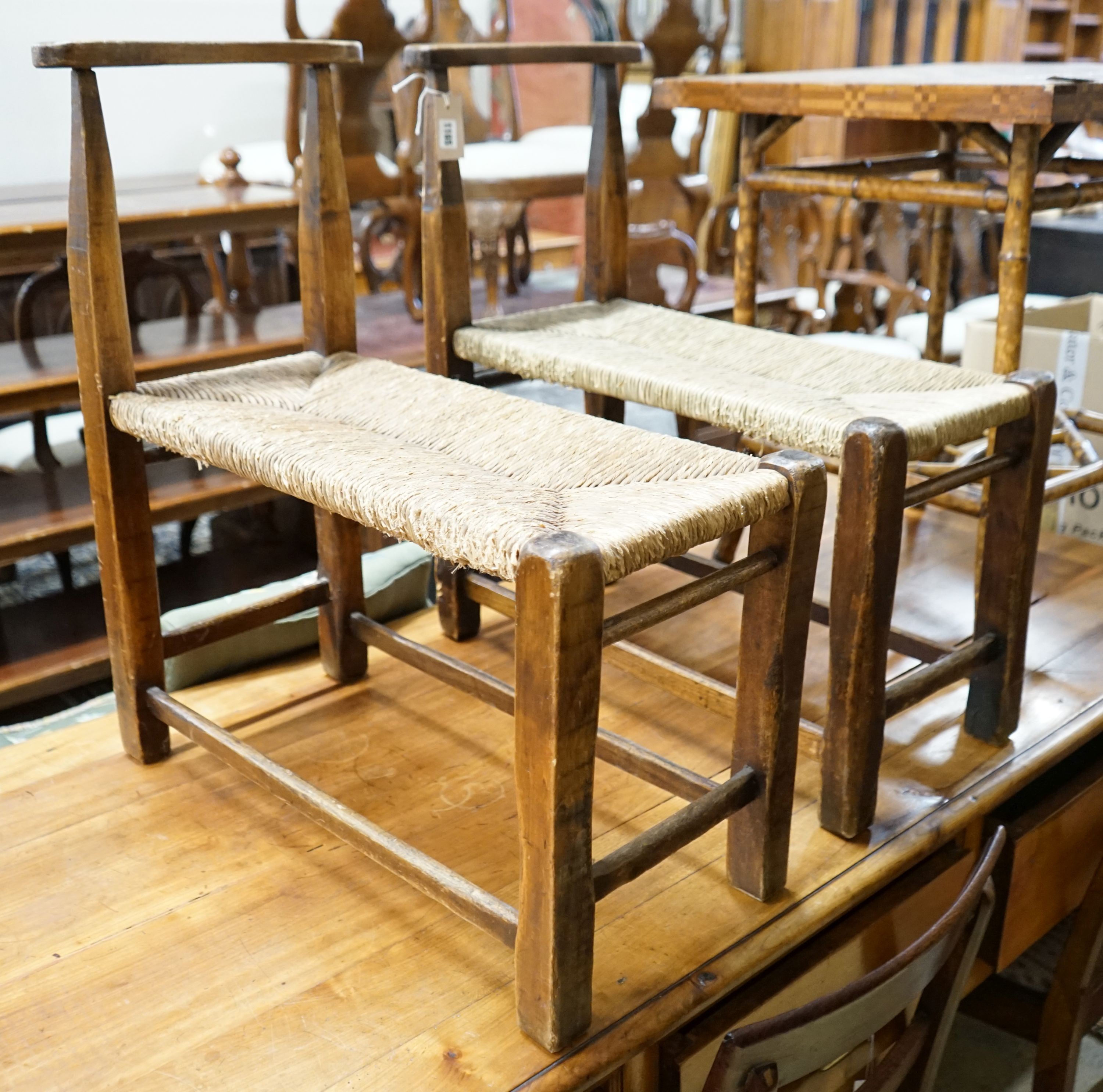 A pair of French provincial oak and beech stools with elongated rush seats, width 31cm, length 67cm, height 73cm